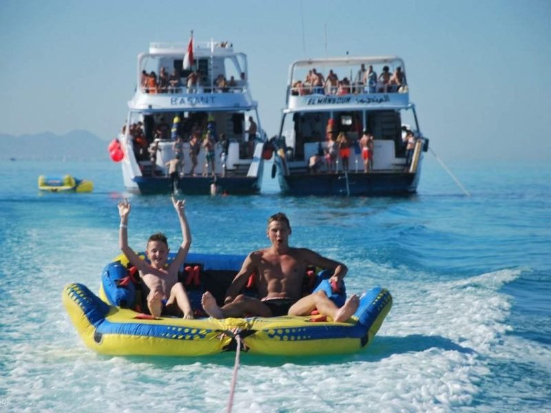 Tourists enjoying a boat trip to Orange Bay Island with snorkeling, water sports, and beachside lunch