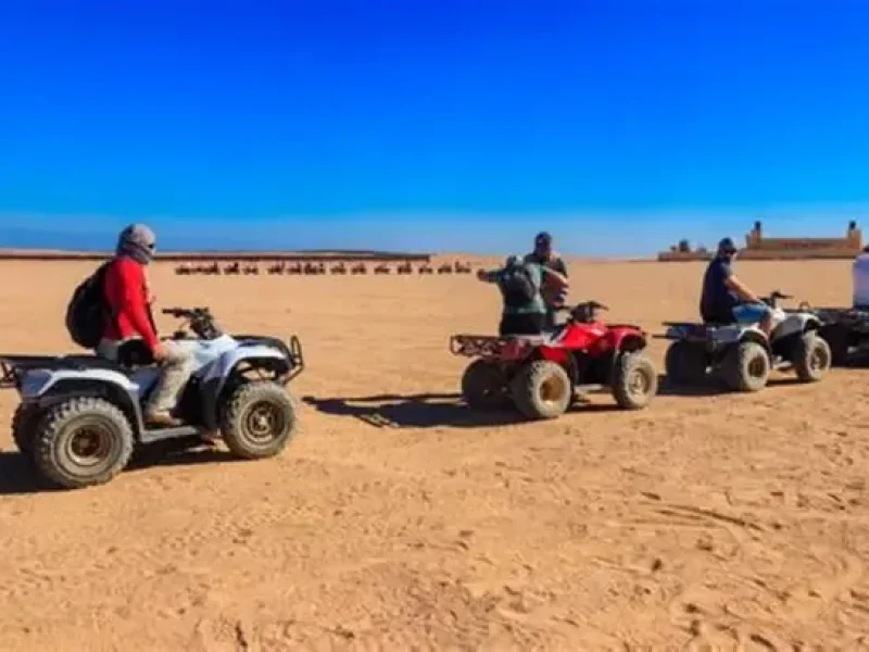 Tourist riding a quad bike through the desert and another enjoying a camel ride during a 3-hour safari adventure